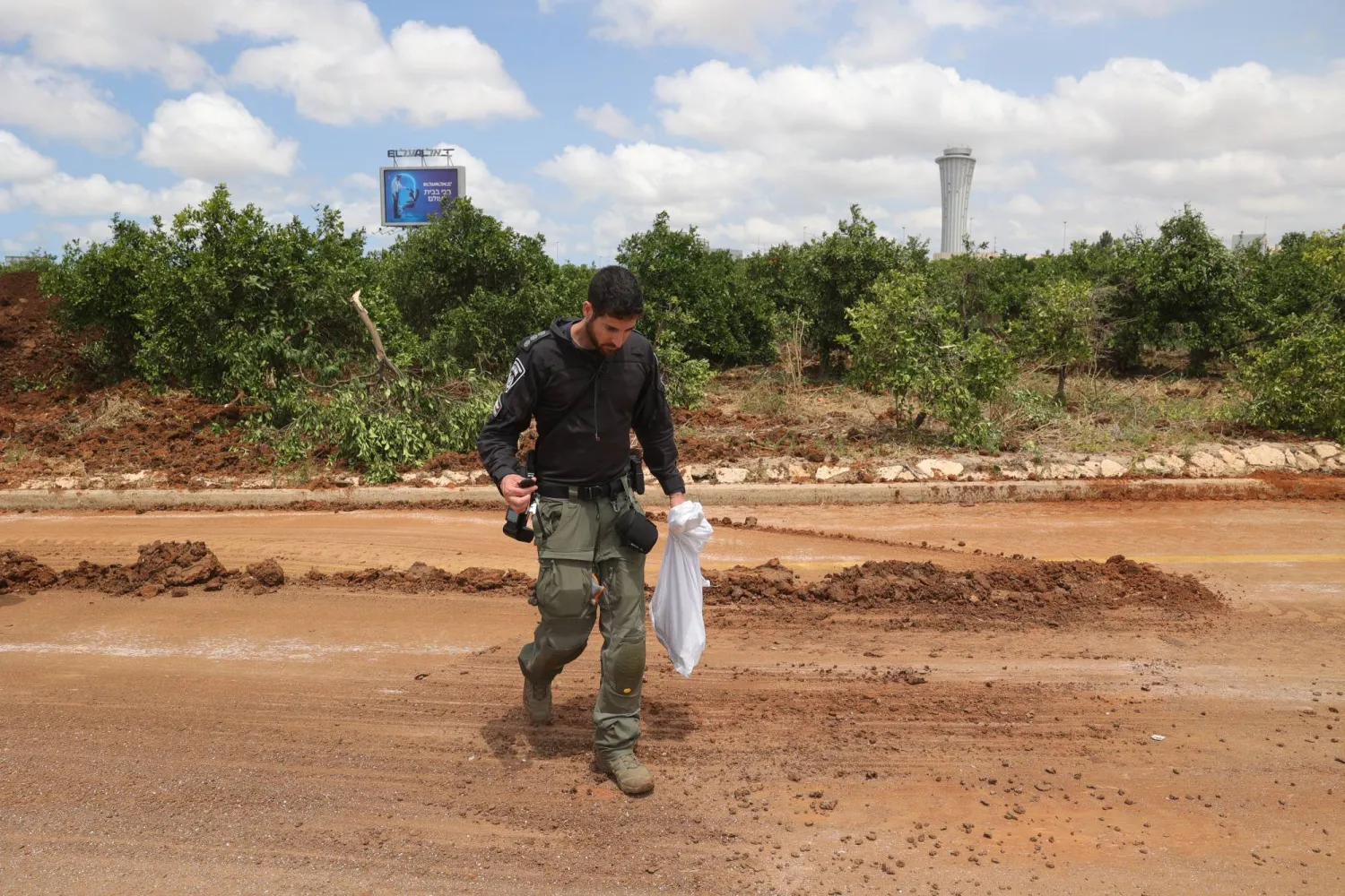 شرطي إسرائيلي يجمع حطاماً من موقع انفجار صاروخ أطلقته جماعة «الحوثي» في اليمن وسقط في محيط مطار بن غوريون (إ.ب.أ)