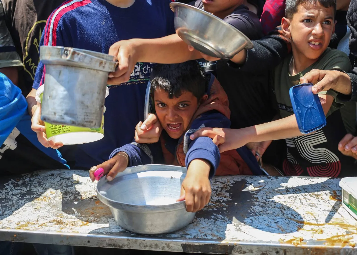 نازحون فلسطينيون يتدافعون للحصول على طعام بمخيم النصيرات للاجئين وسط غزة (أ.ف.ب)