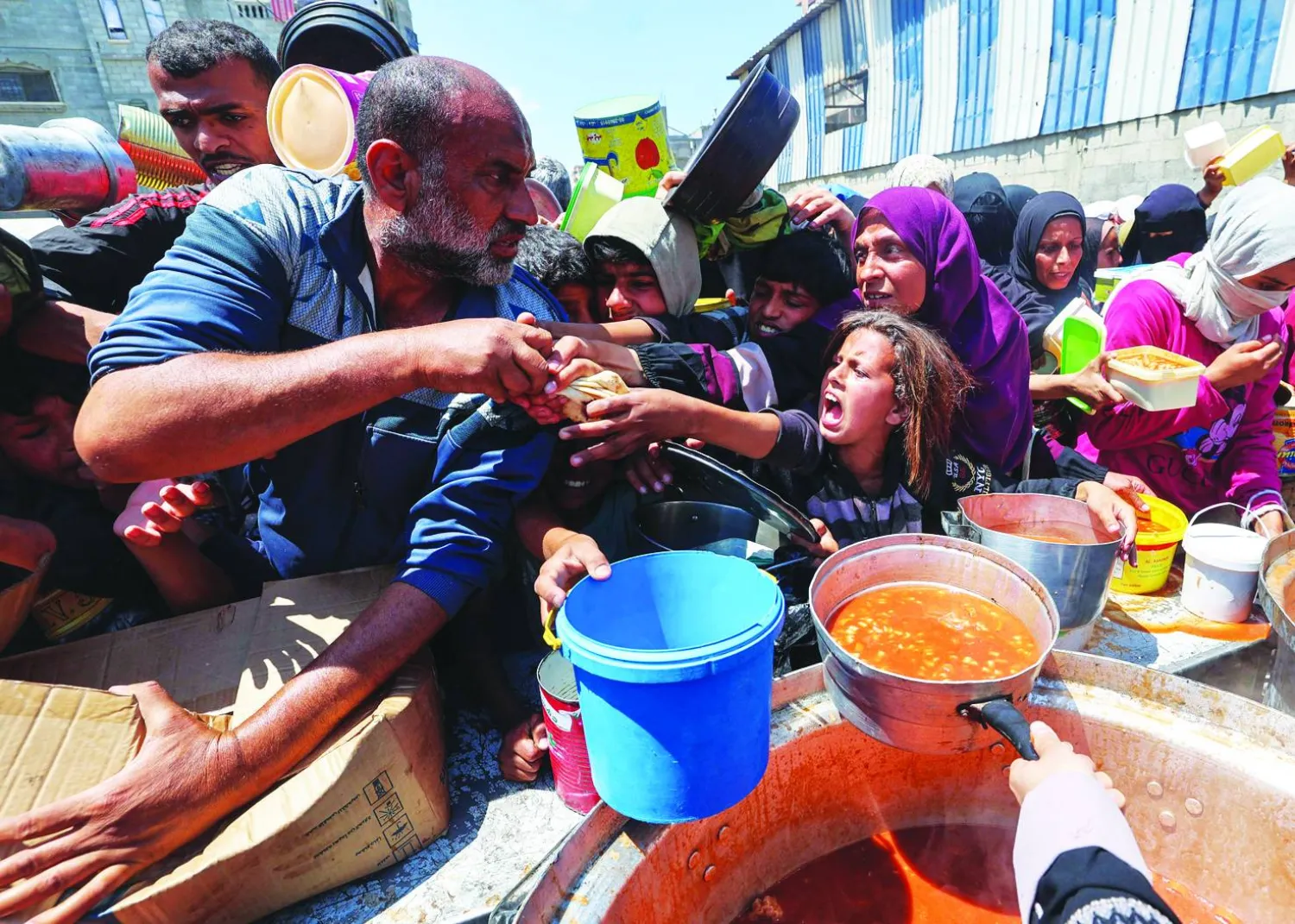 تدافع للحصول على معونة غذائية من مطبخ خيري في مخيم النصيرات وسط قطاع غزة أمس (أ.ف.ب)