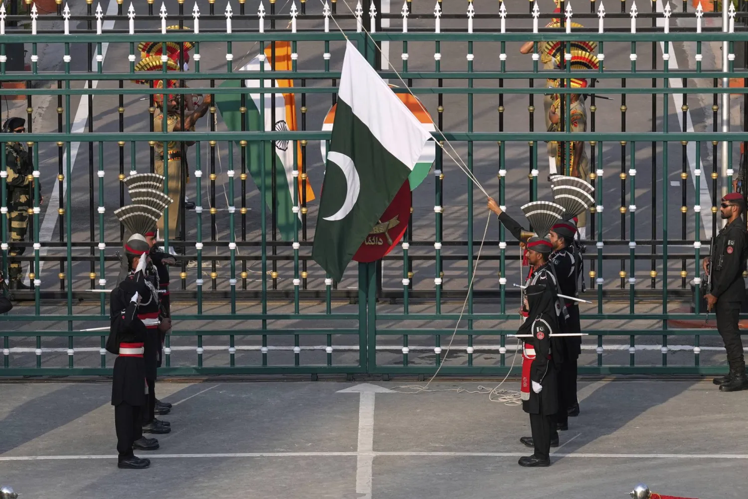 جنود من قوات رينجرز الباكستانية يرتدون ملابس سوداء وفي المقابل جنود من قوات أمن الحدود الهندية خلف البوابة يخفضون أعلامهم خلال حفل ختام يومي في واغا وهو موقع مشترك على الحدود الباكستانية الهندية بالقرب من لاهور في باكستان يوم الاثنين 5 مايو 2025 (أ.ب)