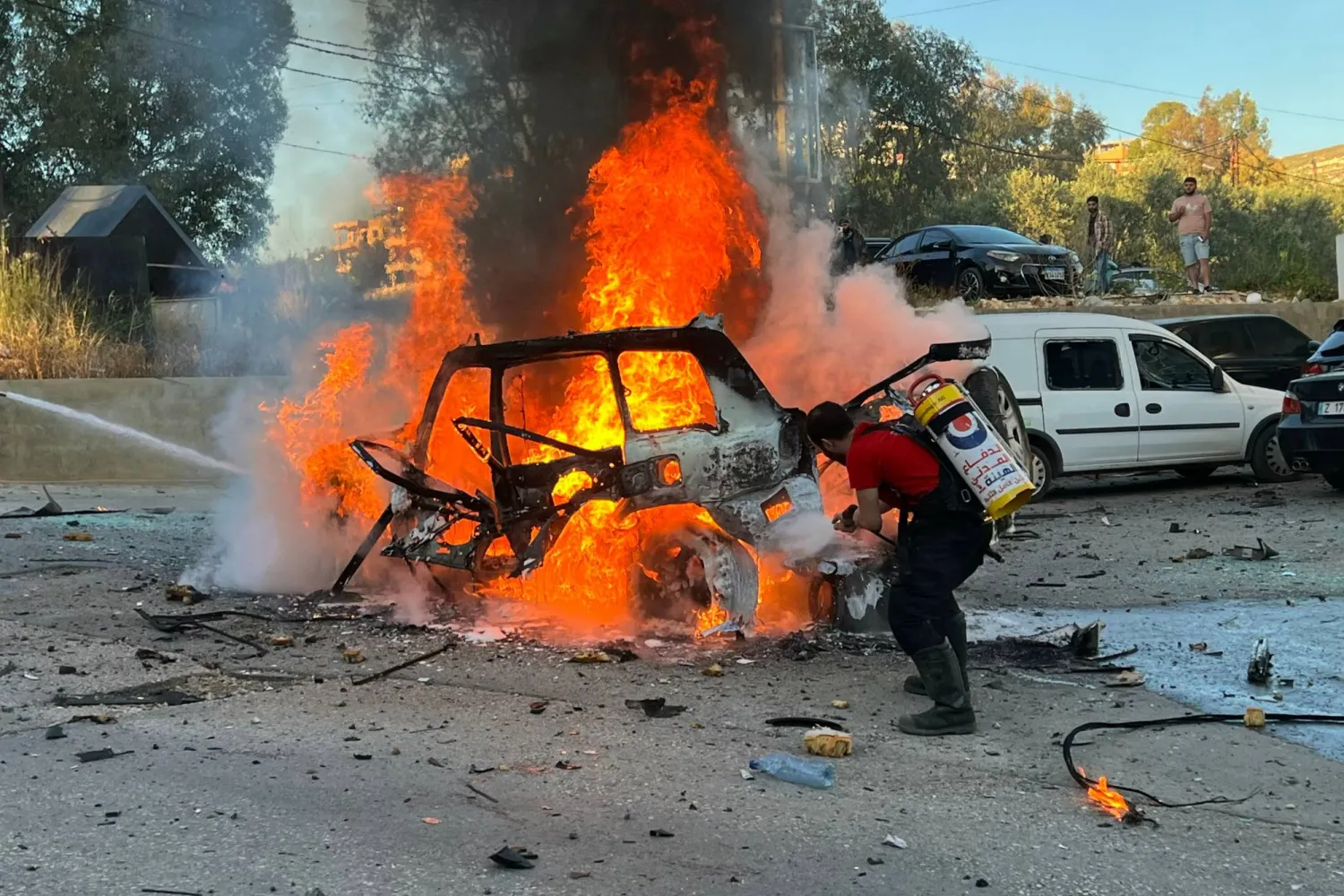 محاولة إطفاء سيارة قصفتها مسيّرة إسرائيلية في بلدة كفررمّان بجنوب لبنان (أ.ف.ب)