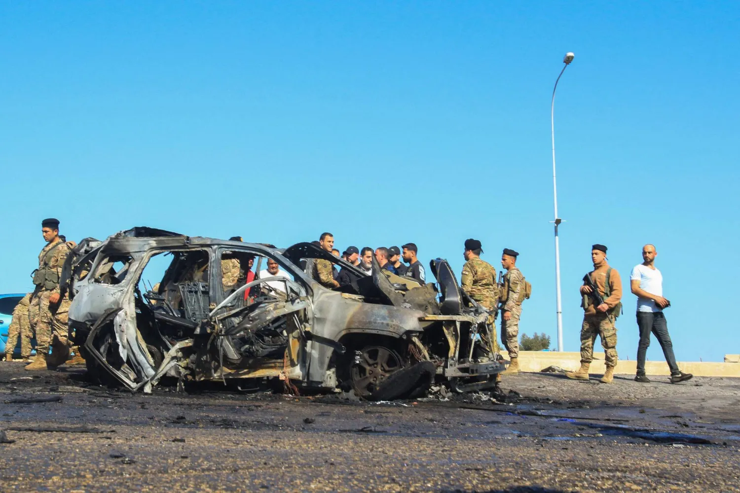 أشخاص يتجمعون أمام السيارة التي استهدفتها غارة إسرائيلية في الغازية قرب صيدا (أرشيفية- أ.ف.ب)