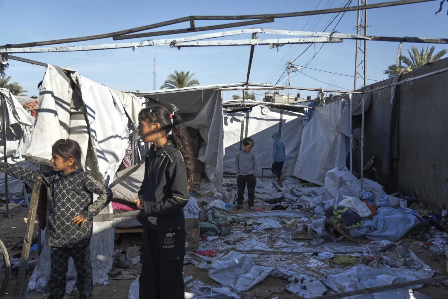 فلسطينيون يتفقدون الأضرار التي سببتها غارة جوية إسرائيلية استهدفت خيام النازحين في دير البلح وسط قطاع غزة (أ.ب)