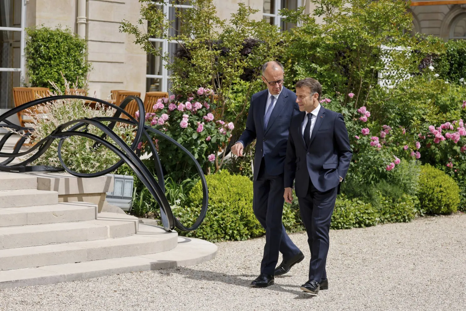  ميرتس يتحدث مع ماكرون بحديقة قصر الإليزيه في باريس (أ.ب)