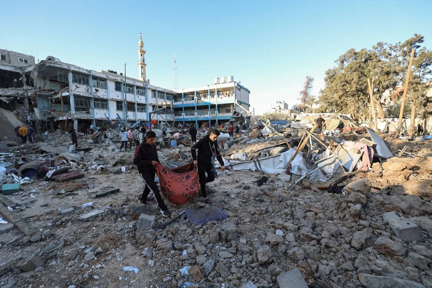 فلسطينيون يحملون جثمان أحد ضحايا غارة إسرائيلية على مدرسة تابعة لـ«الأونروا» تؤوي نازحين في مخيم البريج وسط غزة (أ.ف.ب)