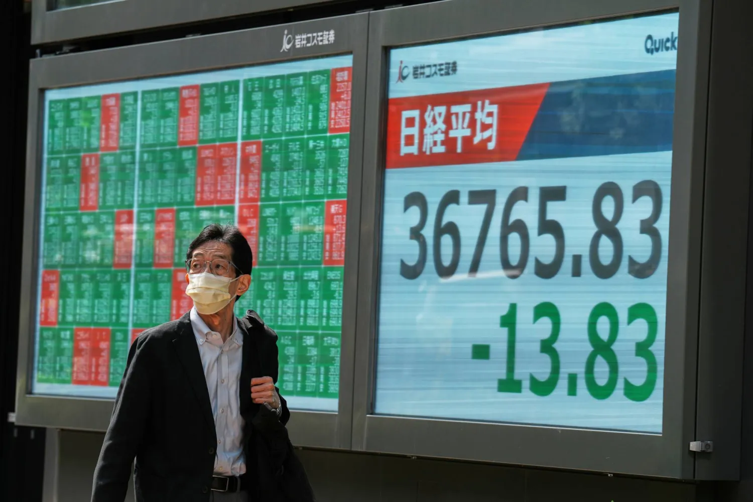 أحد المشاة في شارع بوسط العاصمة اليابانية طوكيو يمر أمام شاشة إلكترونية تعرض حركة الأسهم (أ.ب)