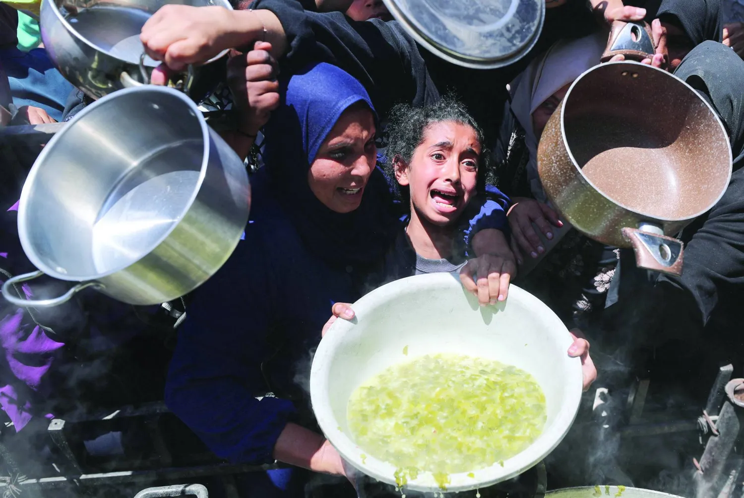 فتاة فلسطينية تكابد مع غيرها للحصول على الطعام من مطبخ خيري في بيت لاهيا شمال غزة أمس (رويترز)