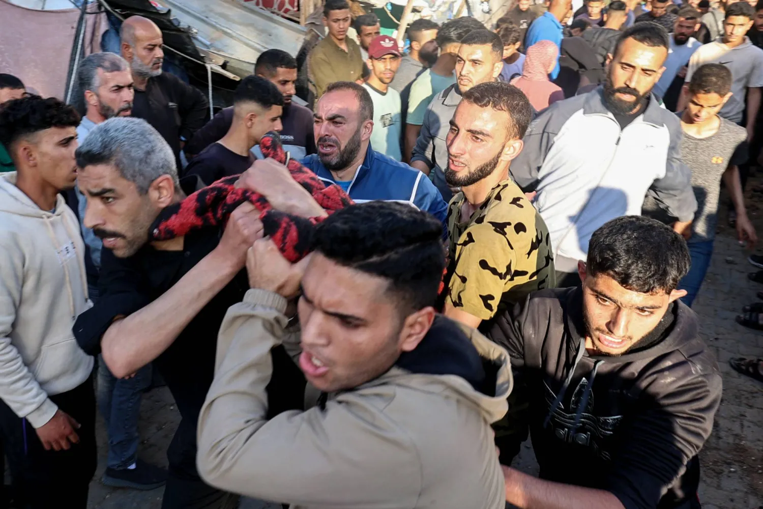 أشخاص يحملون أحد المصابين عقب غارة إسرائيلية على مدرسة تابعة للأونروا وسط قطاع غزة (أ.ف.ب)