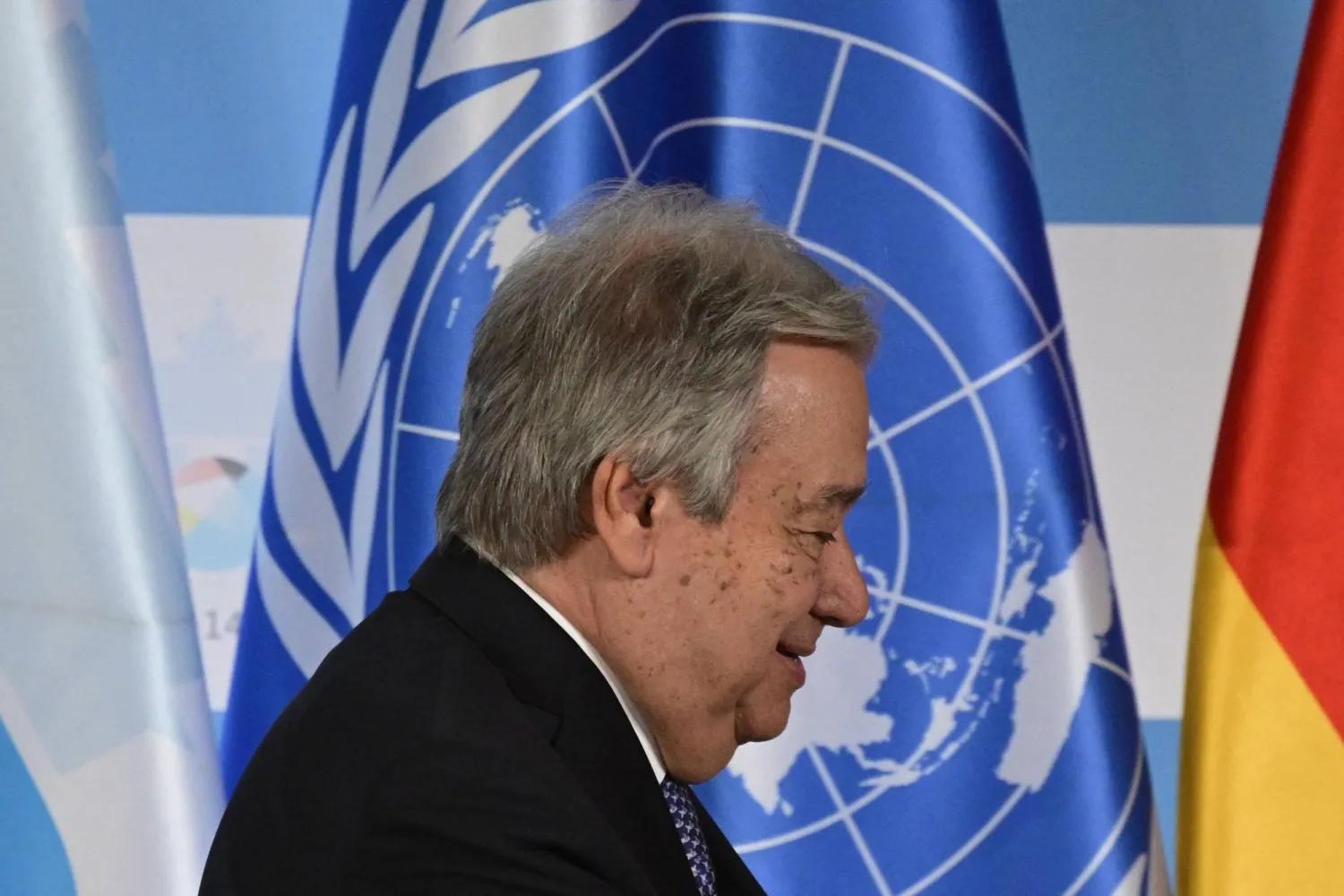 أنطونيو غوتيريش يمر أمام علم الأمم المتحدة في أثناء مغادرته بعد مؤتمر صحافي مشترك خلال اجتماع وزراء حفظ السلام التابعين للأمم المتحدة لعام 2025 في برلين (أ.ف.ب)