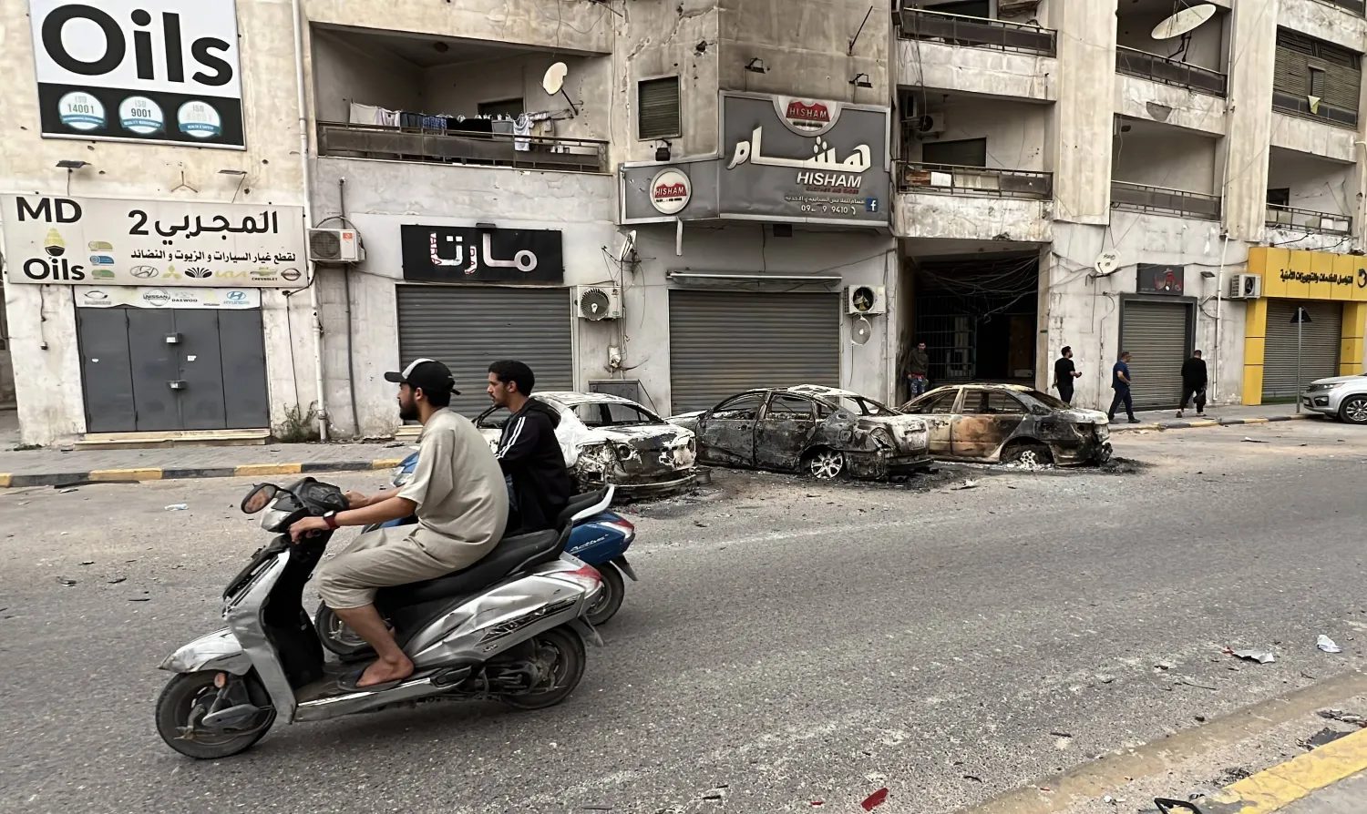 سيارات محترقة على جانب الطريق في طرابلس جراء اشتباكات مسلحة بالعاصمة الليبية (إ.ب.أ) 