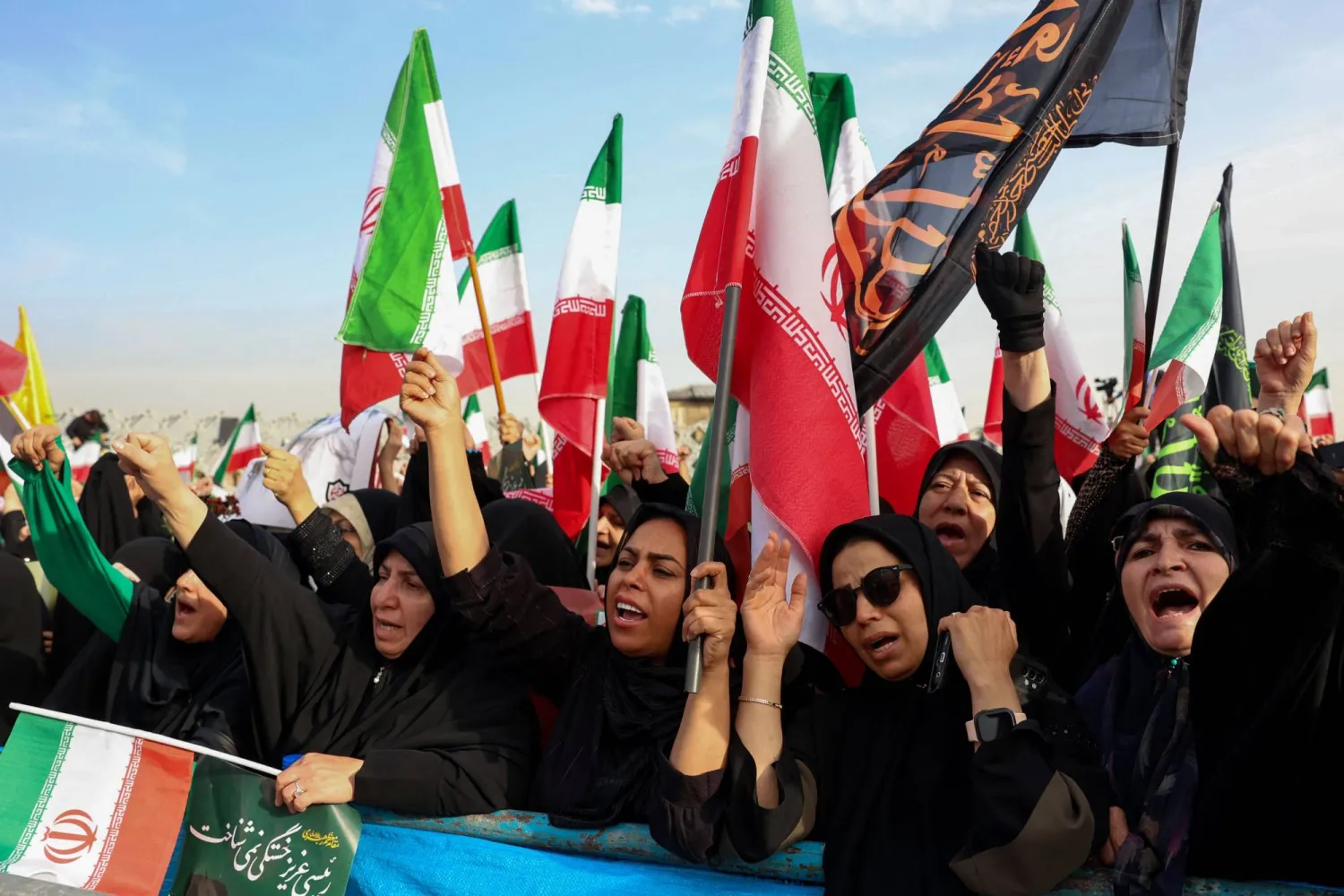 إيرانيات يلوّحن بأعلام خلال إحياء الذكرى الأولى لمقتل الرئيس الإيراني السابق إبراهيم رئيسي في حادث سقوط مروحية (أ.ف.ب)