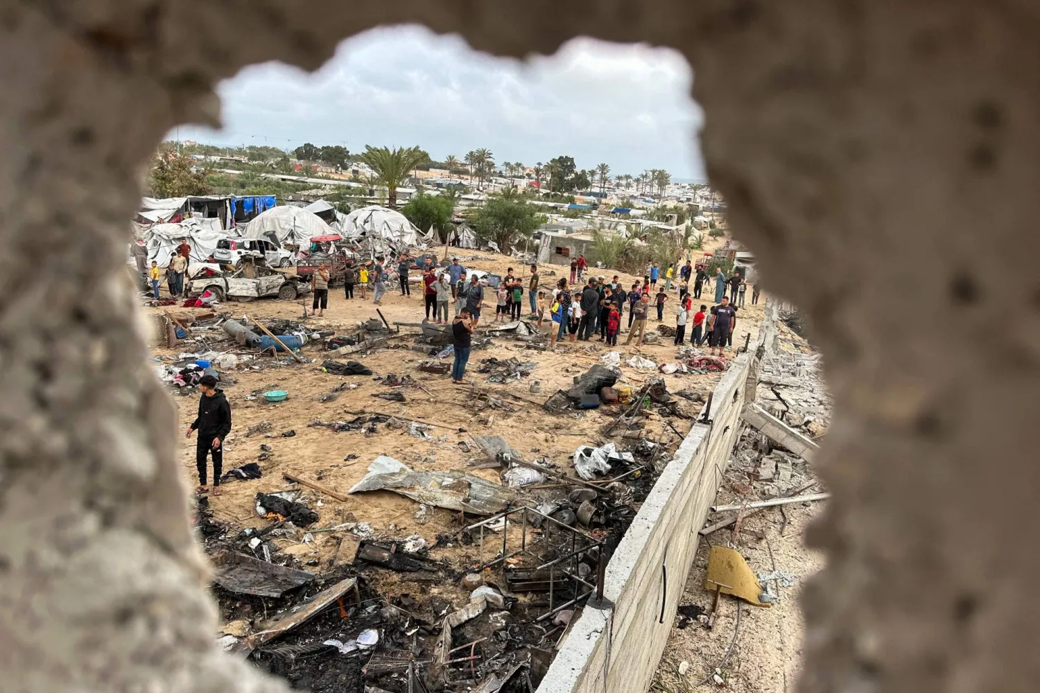 فلسطينيون في موقع غارات إسرائيلية على منطقة المواصي بغرب خان يونس في جنوب قطاع غزة (أ.ف.ب)