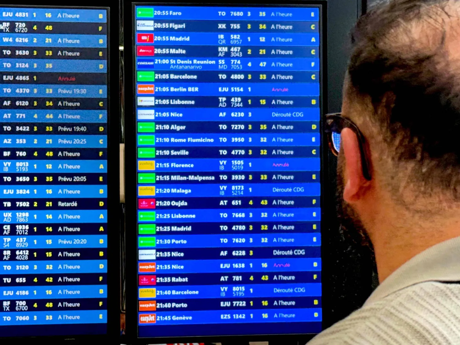 A traveler looks at a flights information board during a breakdown in air traffic control systems at Paris-Orly airport in Orly, South of Paris, on May 18, 2025. (Photo by Aurore MESENGE / AFP)