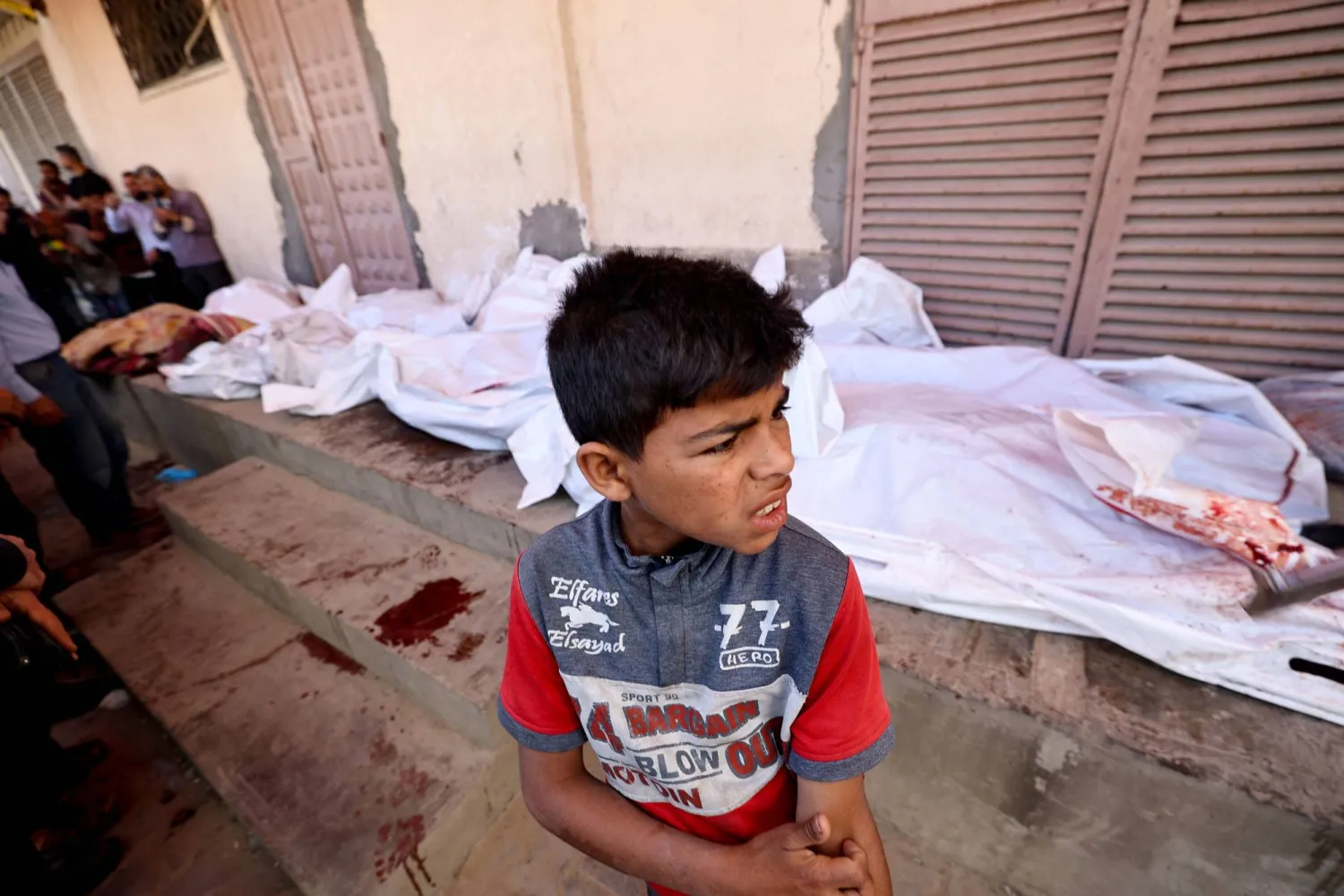 A boy gestures as he stands near the bodies of Palestinians killed in Israeli strikes, at the al-Aqsa Martyrs hospital in Deir el-Balah in the central Gaza Strip on May 20, 2025. (Photo by Eyad BABA / AFP)