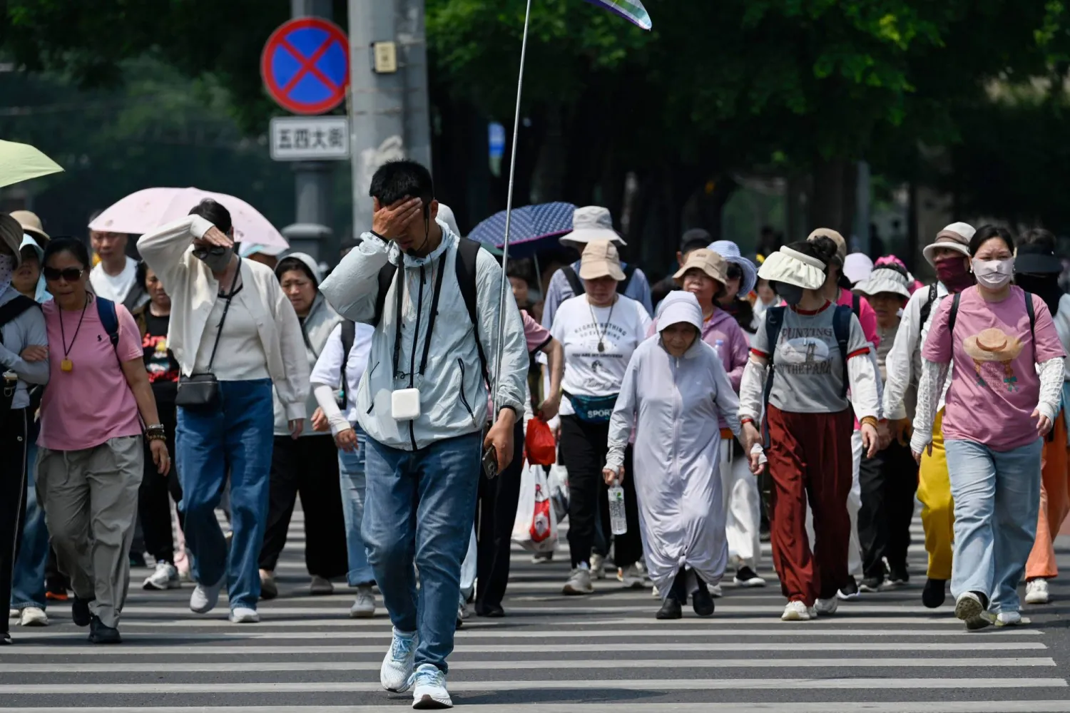 مرشد سياحي يقود فوجاً سياحياً بأحد شوارع العاصمة الصينية بكين (أ.ف.ب)
