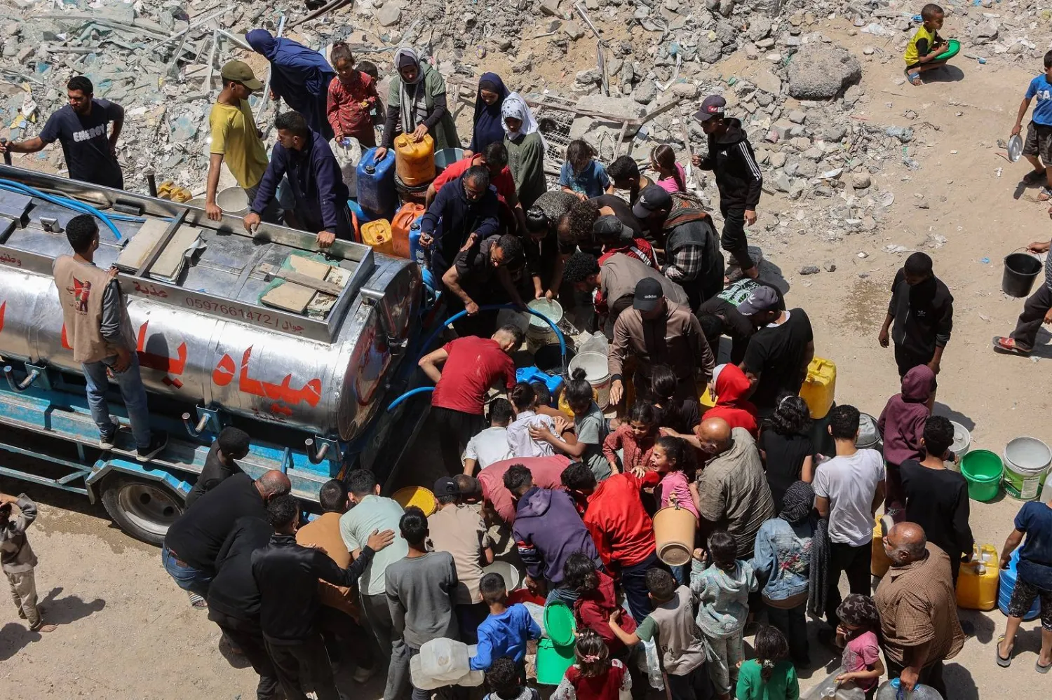 فلسطينيون يصطفون لملء حاوياتهم بالمياه في حي الرمال بمدينة غزة (أ.ف.ب)