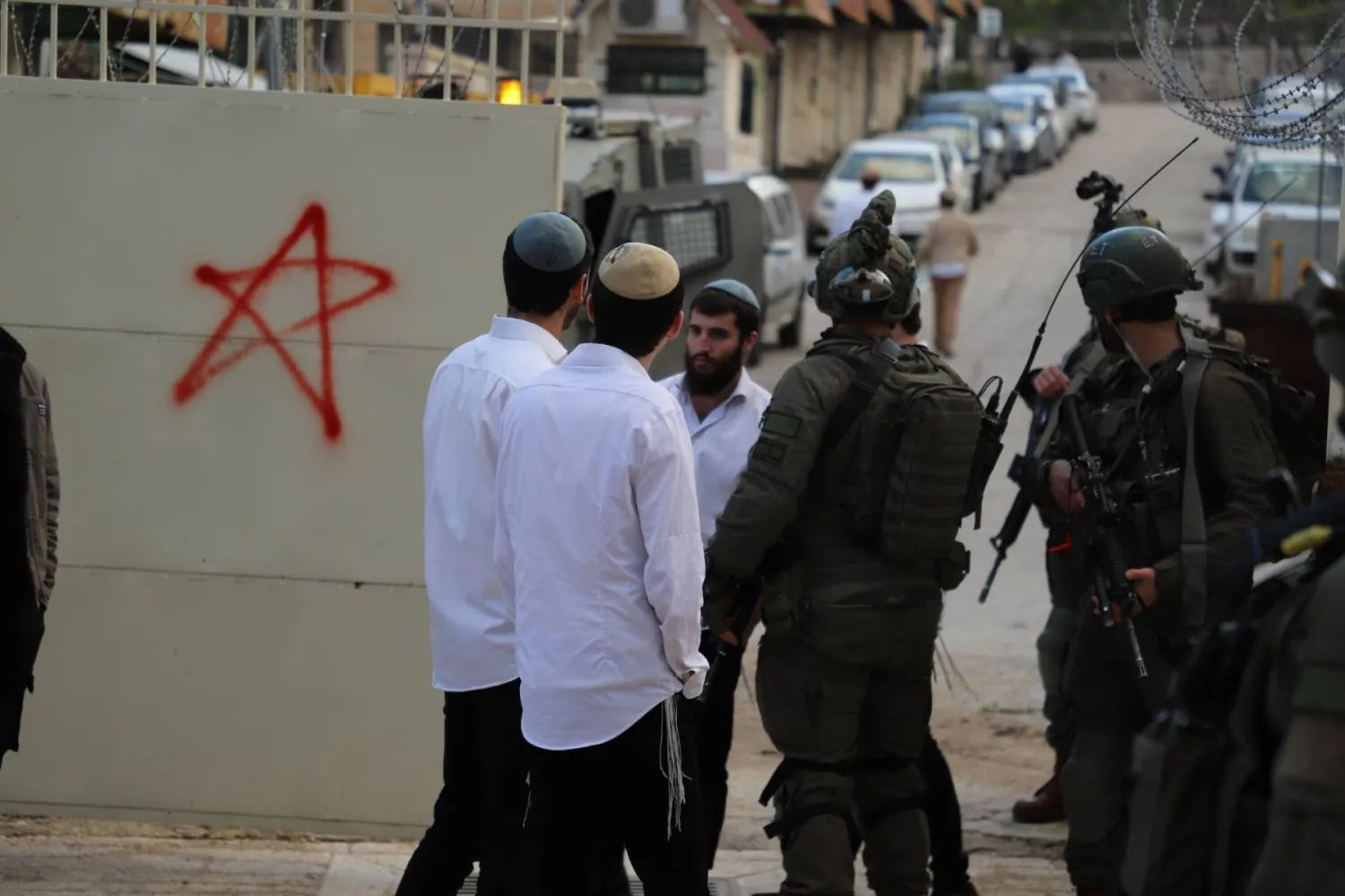 مستوطنون يقفون إلى جانب جنود إسرائيليين (أرشيفية - رويترز)