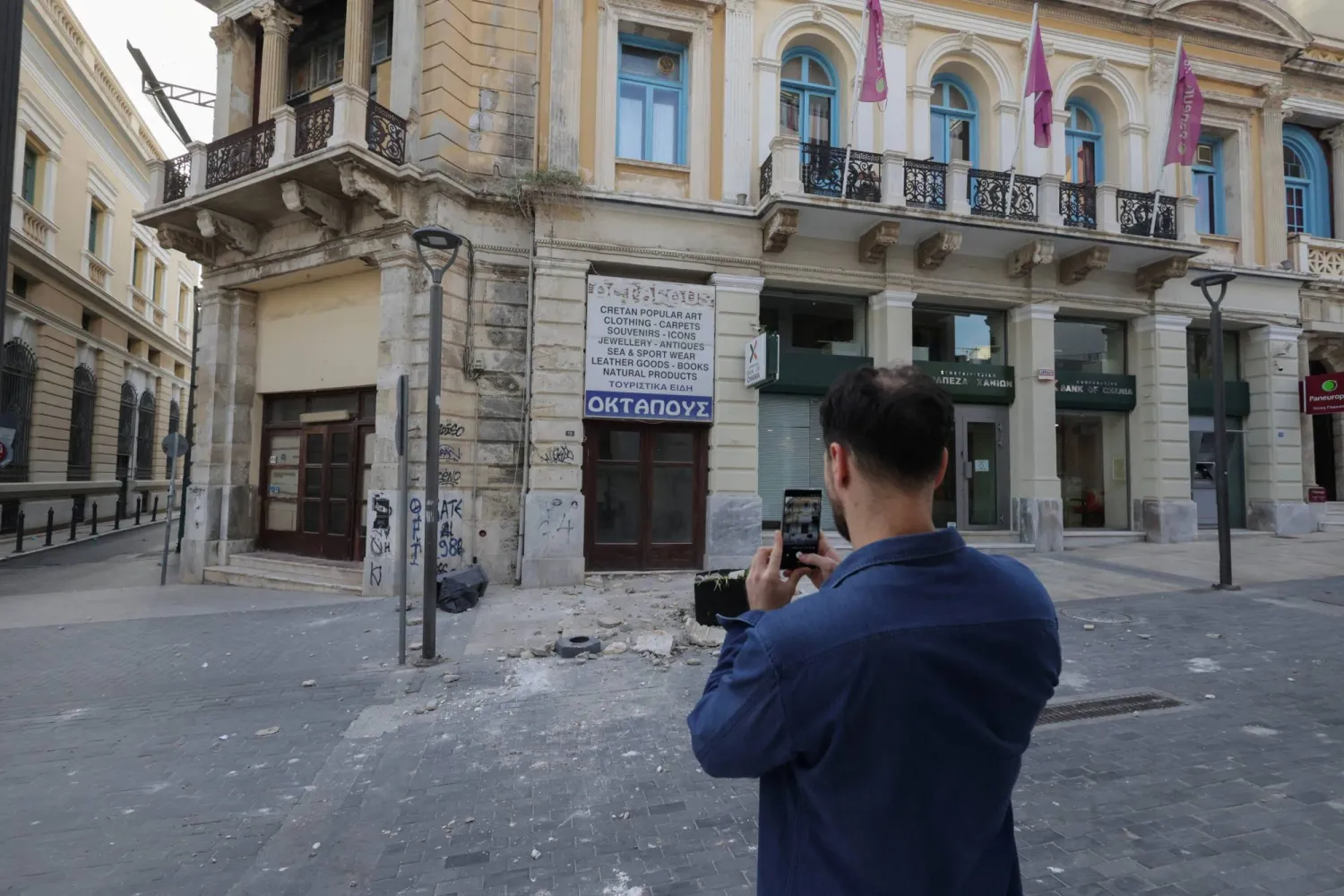 A man takes photos of a damaged building, following an earthquake that hit the island of Crete, in Heraklion, Greece, May 22, 2025. REUTERS/Costas Metaxakis
