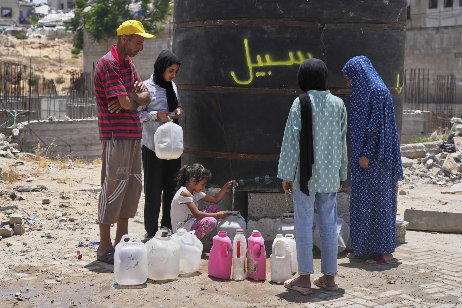 فلسطينيون يملأون حاويات بالمياه في مدينة غزة (أ.ب)