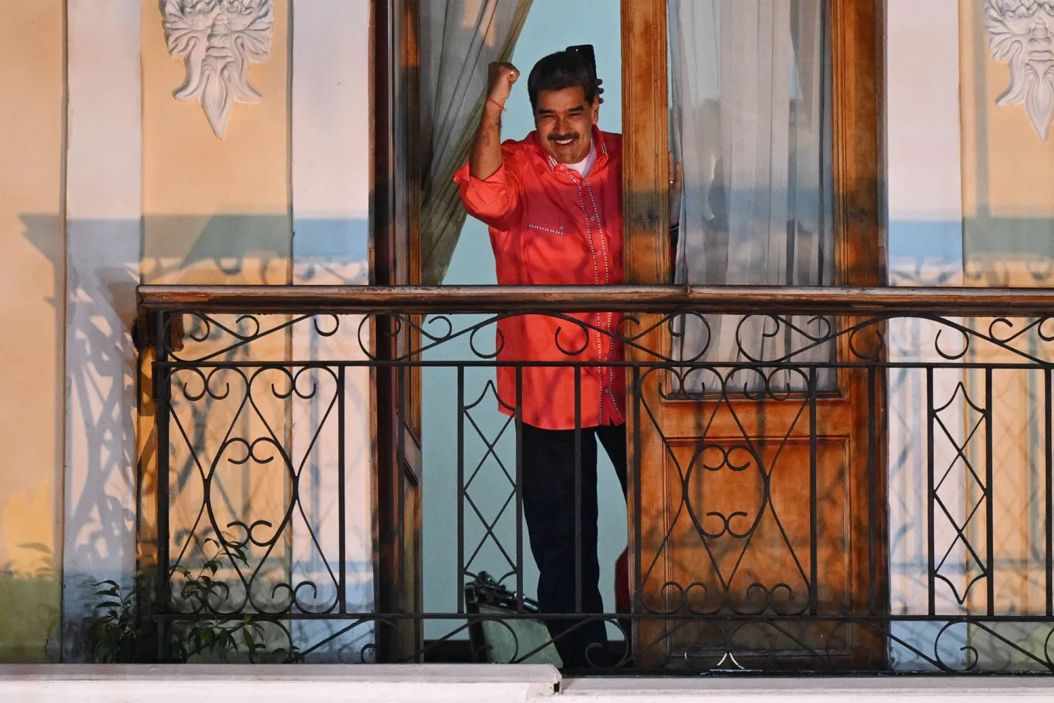 Venezuelan President Nicolas Maduro (C) waves to supporters from a balcony as he celebrates the results of the parliamentary and regional elections at the Bolivar square in Caracas on May 25, 2025. (Photo by Federico PARRA / AFP)