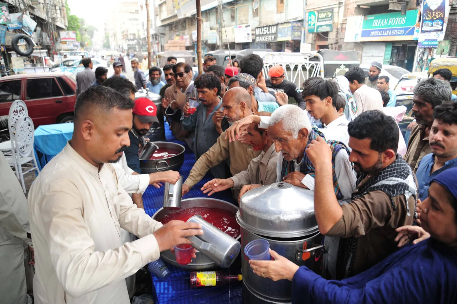 يشرب الناس عصيراً مجانياً في مخيم على جانب الطريق أقامته منظمة «أنا أمتلك» المحلية في حيدر آباد باكستان في 26 مايو 2025 (إ.ب.أ)