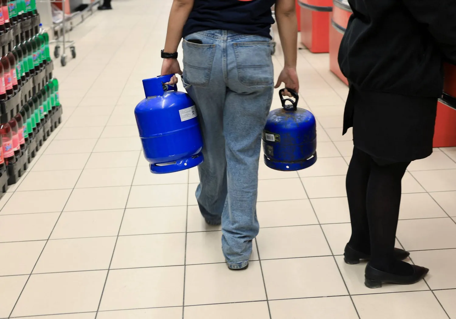 شخص يحمل أسطوانات غاز في سوبر ماركت في كيب تاون بجنوب أفريقيا (رويترز)