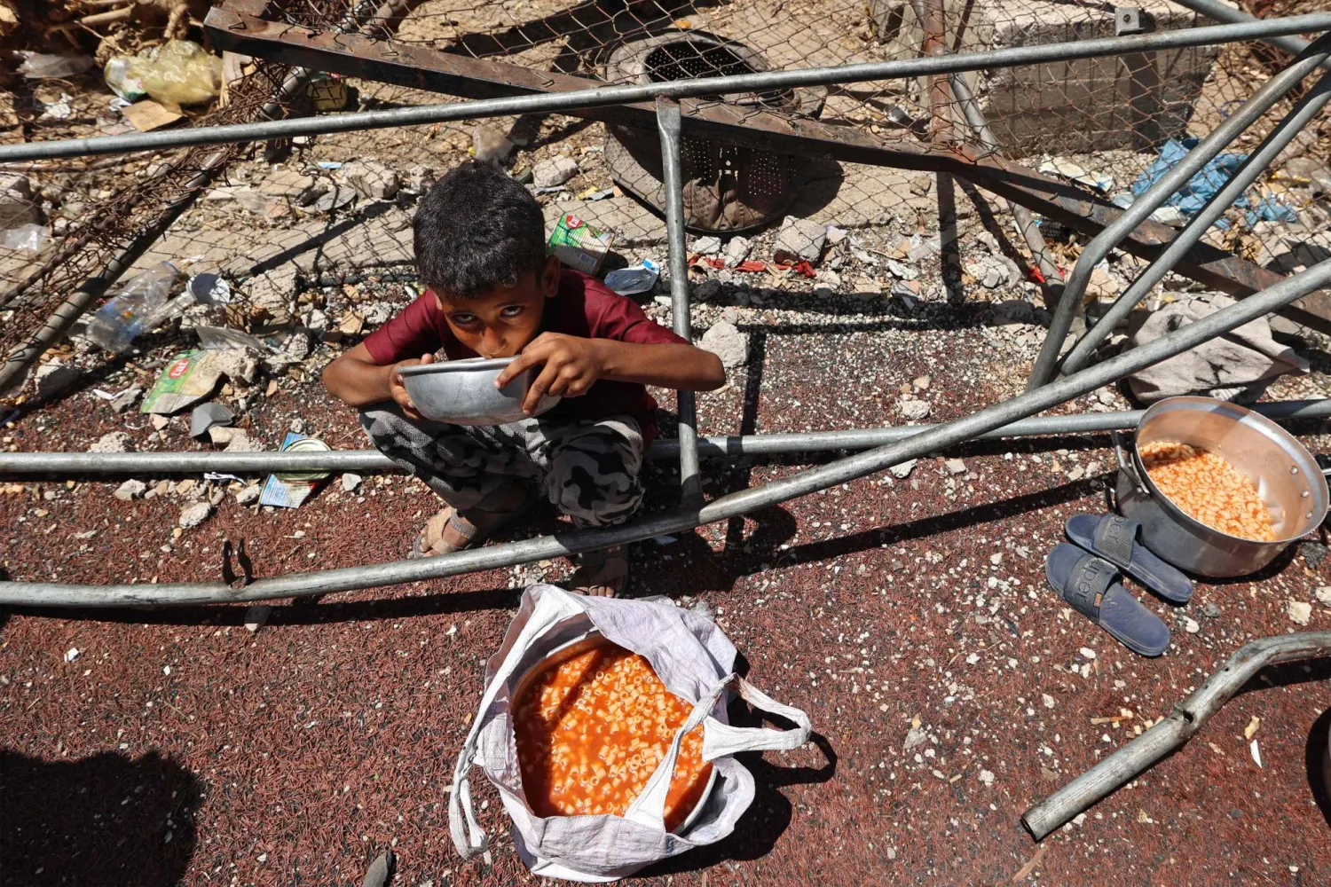 طفل فلسطيني يتناول طعاماً حصل عليه من إحدى التكيات في النصيرات (أ.ف.ب)