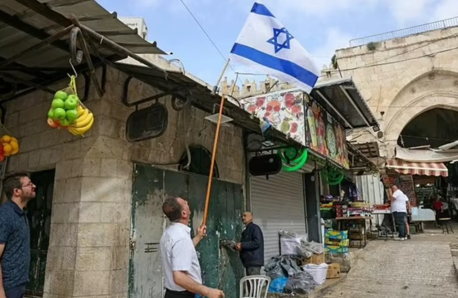 An Israeli flag is removed from above a Palestinian-owned shop in the wake of Jerusalem Day - AFP