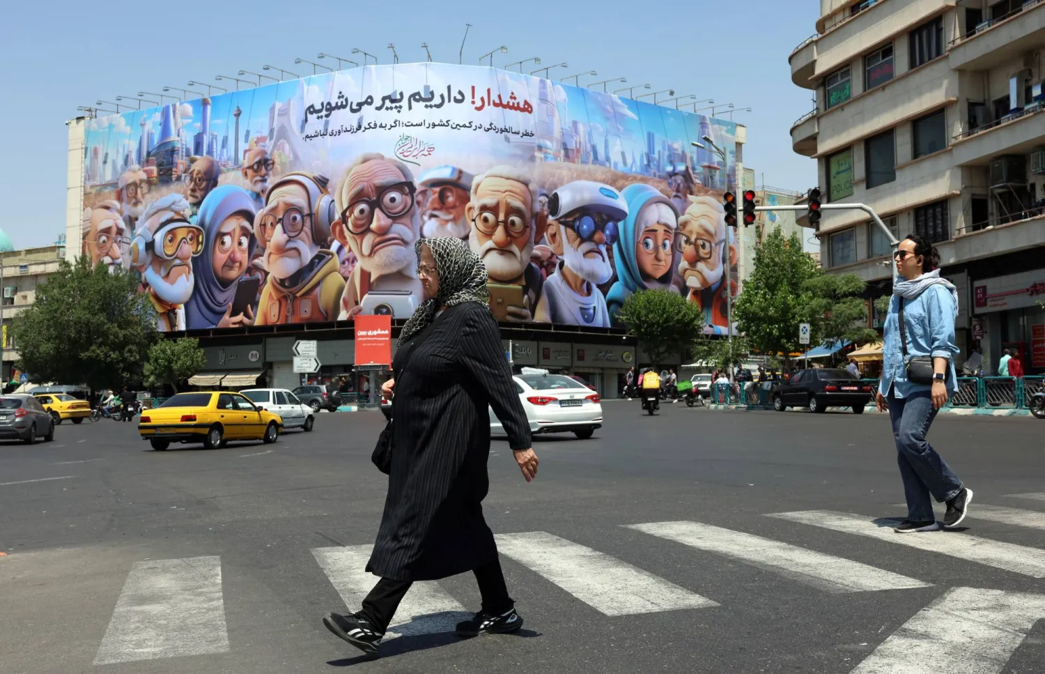 Iranians cross the street past a billboard that reads in Persian 'Warning, we are getting old', referring to the aging population in the country, in Enqelab square, in Tehran, Iran, 26 May 2025. EPA/ABEDIN TAHERKENAREH