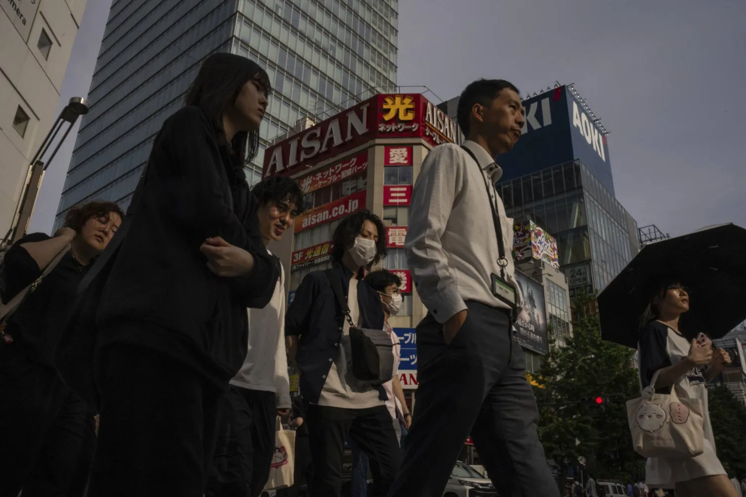 مشاة يعبرون الطريق في أحد الشوارع الرئيسية بوسط طوكيو (أ.ب)