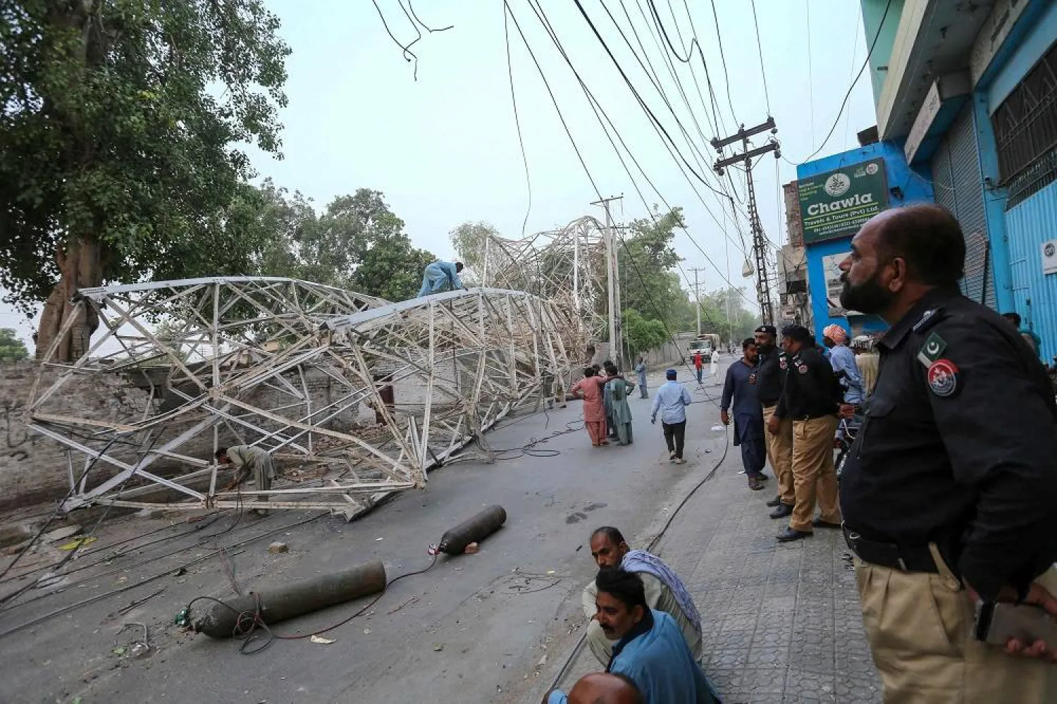 Pakistani policemen look on as workers remove a fallen railway tower after a storm in Multan on May 28, 2025. (AFP) 