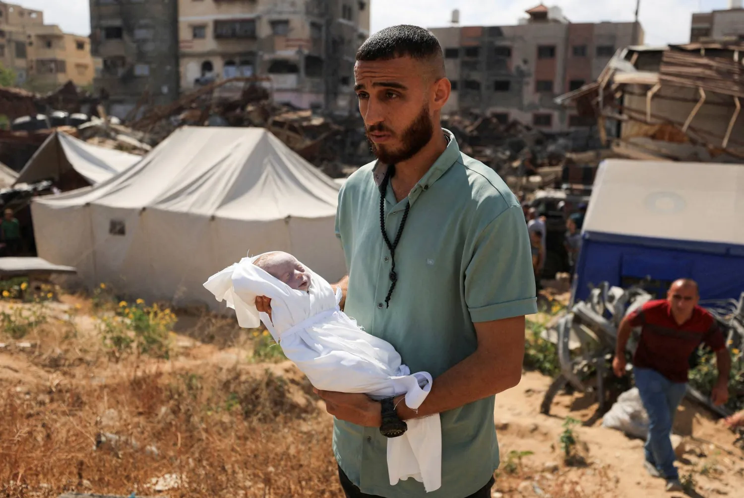 يحمل مشيّع فلسطيني جثمان الطفلة الفلسطينية سهام العرابيد التي قُتلت في غارة إسرائيلية وفقاً للمسعفين في مقبرة بمدينة غزة (رويترز)