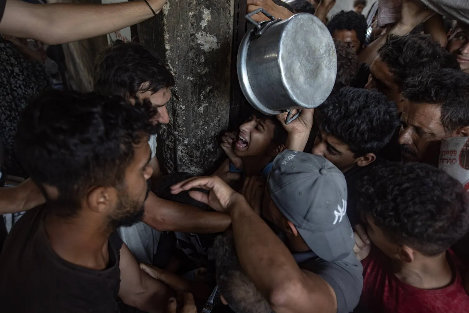 مئات الفلسطينيين النازحين داخلياً يتجمعون أمام مطبخ خيري بمدينة غزة لتلقي حصص غذائية محدودة (إ.ب.أ)