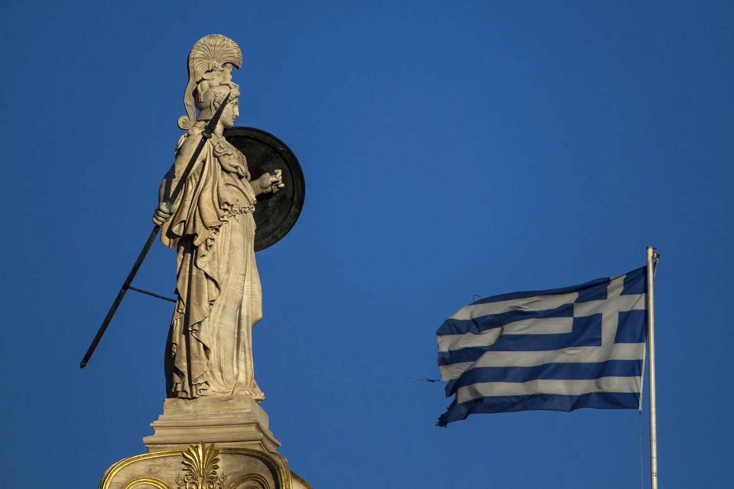 العَلم اليوناني يرفرف أمام تمثال أثينا (د.ب.أ)