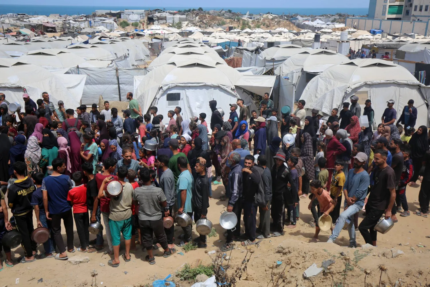 فلسطينيون ينتظرون للحصول على وجبات ساخنة أعدتها جمعيات خيرية في مدينة غزة أمس (د.ب.أ)