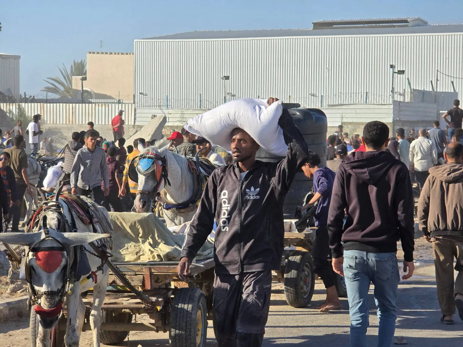 A man carries a sack as people gather at an aid distribution center in Deir Al-Balah, in the Gaza Strip, May 28, 2025.  Obtained by Reuters/via REUTERS  
