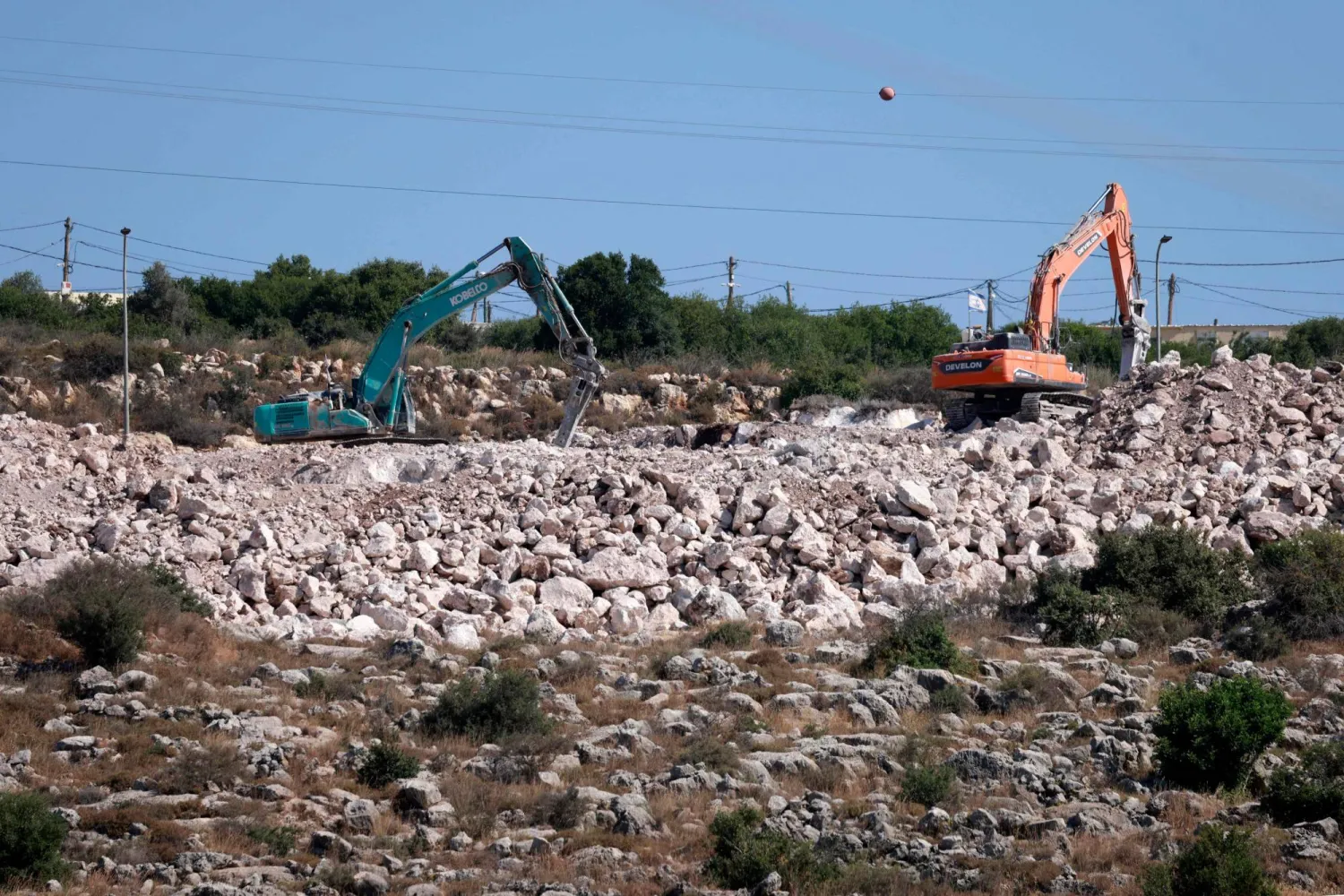 Israeli settlers use excavators to dig the ground in the Palestinian village of Bruqin, outside the walls of an illegal settlement of the same name, in the occupied-West Bank on May 23, 2025. (Photo by Jaafar ASHTIYEH / AFP)