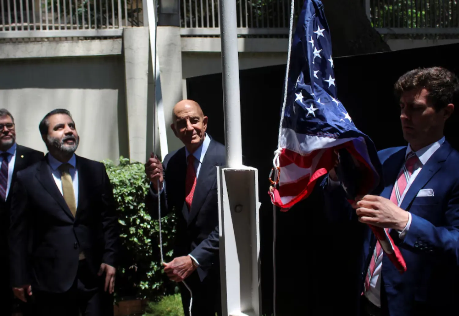 Syrian Foreign Minister Asaad Hassan al-Shibani stands next to US envoy for Syria Thomas Barrack as he raises the American flag at US ambassador's residency in Damascus, Syria May 29, 2025. REUTERS/Firas Makdesi 