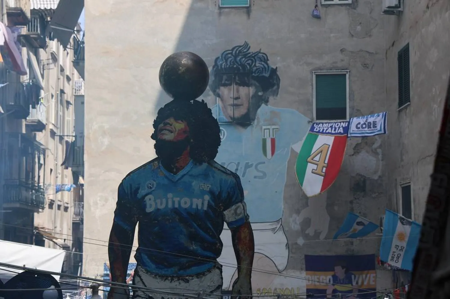 People gather at the "D10S", a 6.20-metre-high statue dedicated to Diego Armando Maradona, created by Salvador Gaudenti and being inaugurated in the Quartieri Spagnoli, in the heart of Naples, after Napoli won the Italian football championship Serie A for the fourth time, Naples, Italy, 24 May 2025. (EPA)