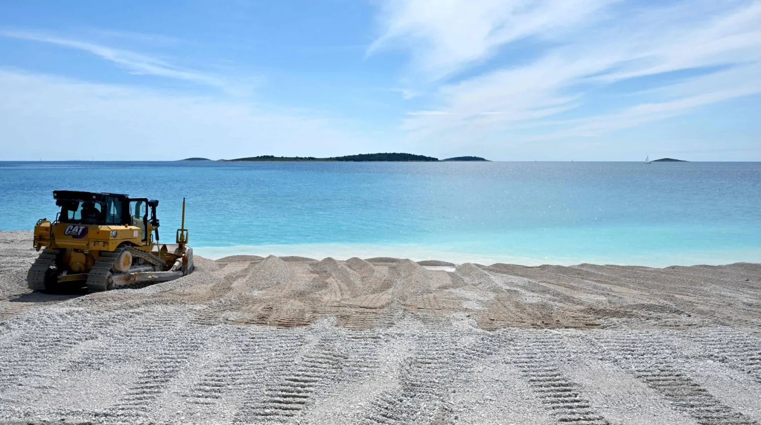 This photograph shows a bulldozer dredging stones to restore the artificial beaches of Primosten a coastal town in Croatia on May 9, 2025. (Photo by ELVIS BARUKCIC / AFP)
