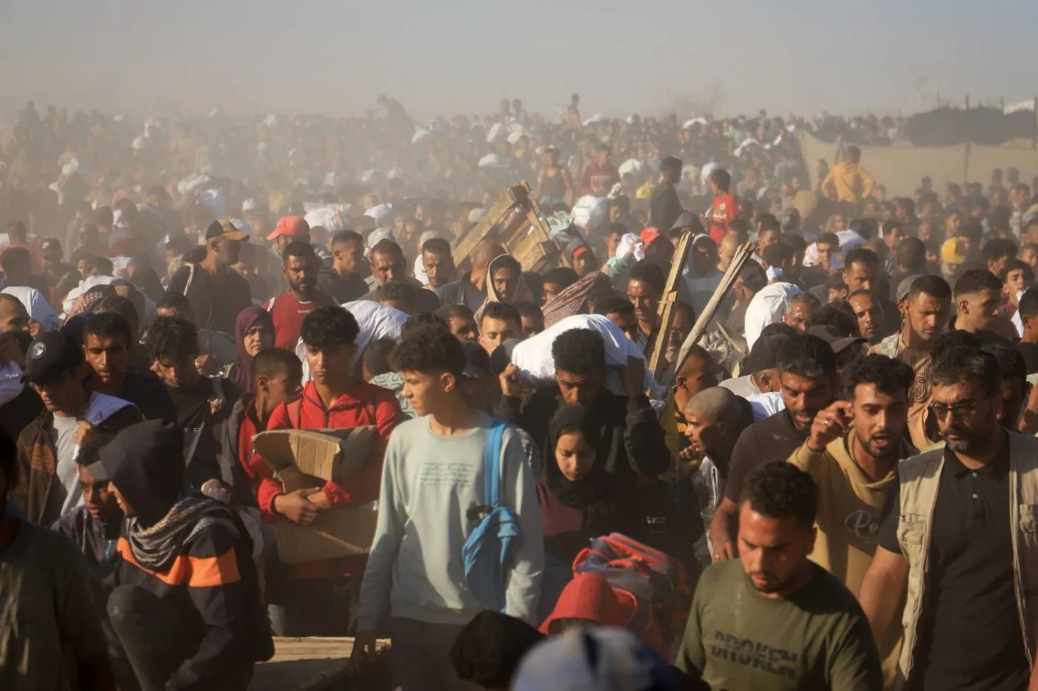 حشود من مواطني غزة تتجه لتسلم مساعدات غذائية (رويترز)