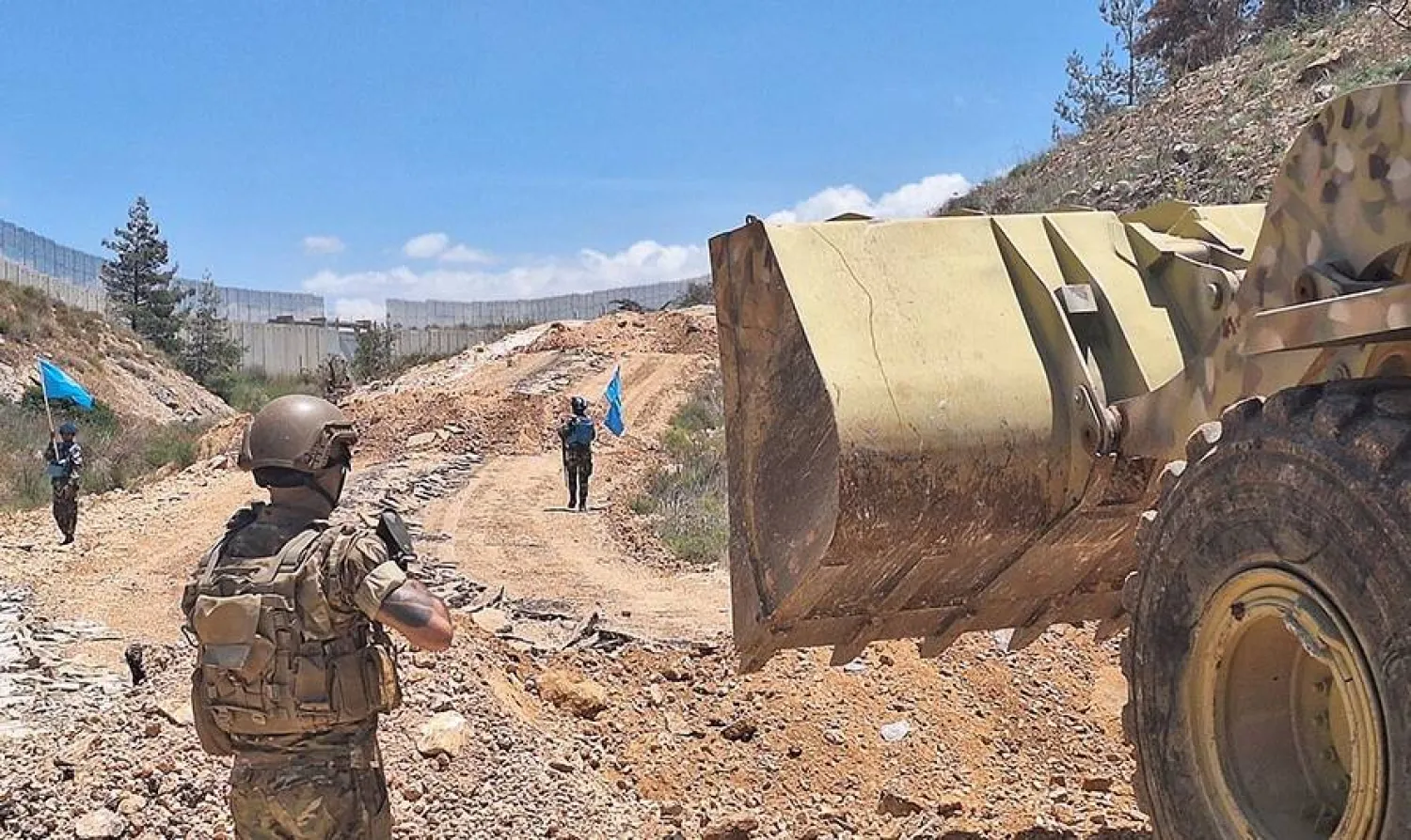 جندي في الجيش اللبناني وعناصر من الـ«يونيفيل» يرافقون آلية للجيش تزيل سواتر ترابية استحدثها الجيش الاسرائيلي في بلدة العديسة بجنوب لبنان (قيادة الجيش)
