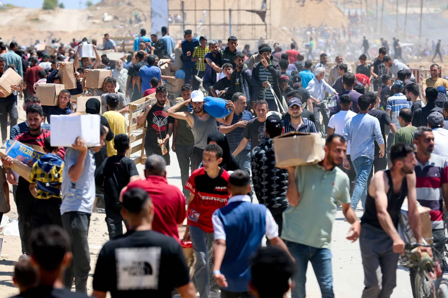 فلسطينيون يحملون إمدادات مساعدات تلقّوها من «مؤسسة غزة الإنسانية» بوسط قطاع غزة (رويترز)