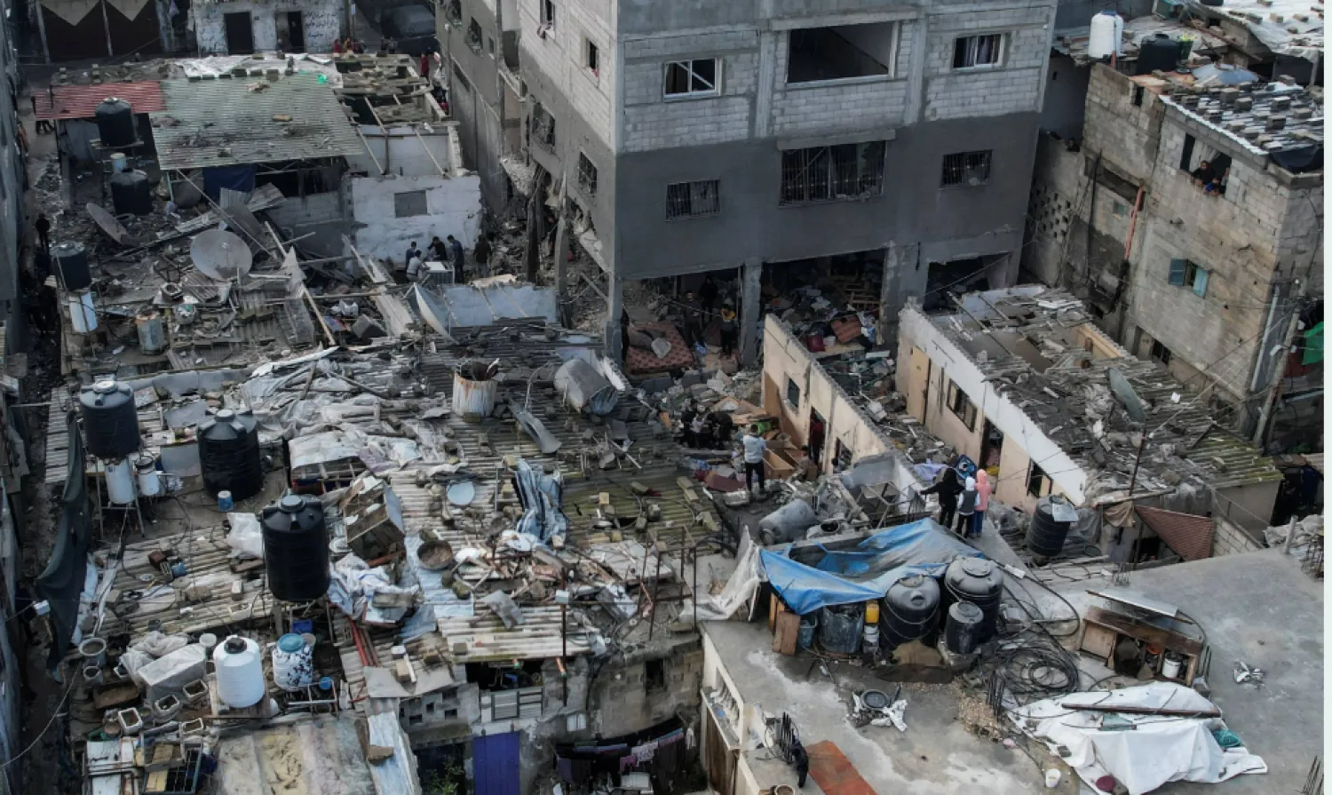 فلسطينيون خلال تجمعهم في موقع غارة إسرائيلية على منزل خلال وقت سابق (رويترز)