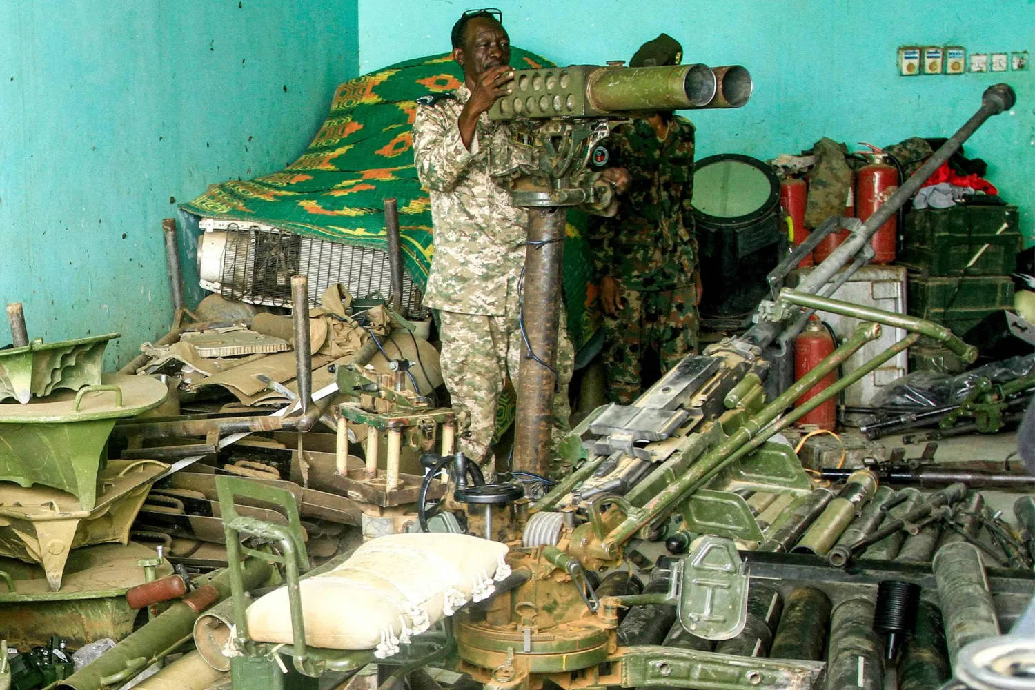 جندي سوداني يستعرض معدات عسكرية استولى عليها الجيش في منطقة صالحة بأم درمان (أ.ف.ب)