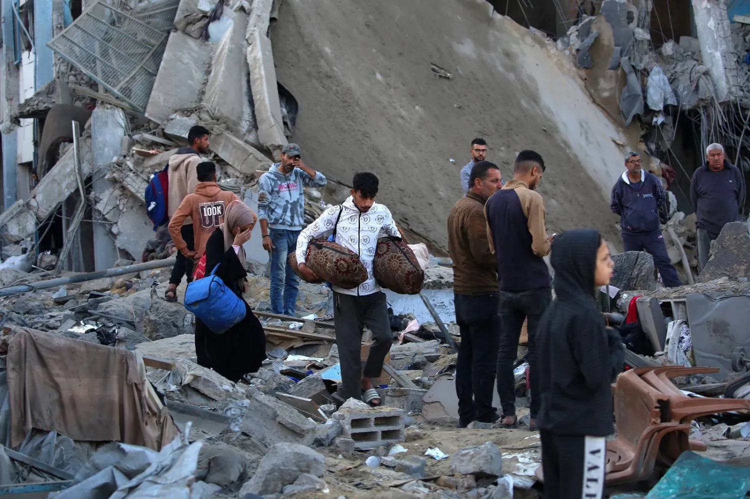 فلسطينيون يفحصون الملاجئ المدمرة في مدرسة تابعة لـ«الأونروا» تؤوي نازحين وسط قطاع غزة (أ.ف.ب)