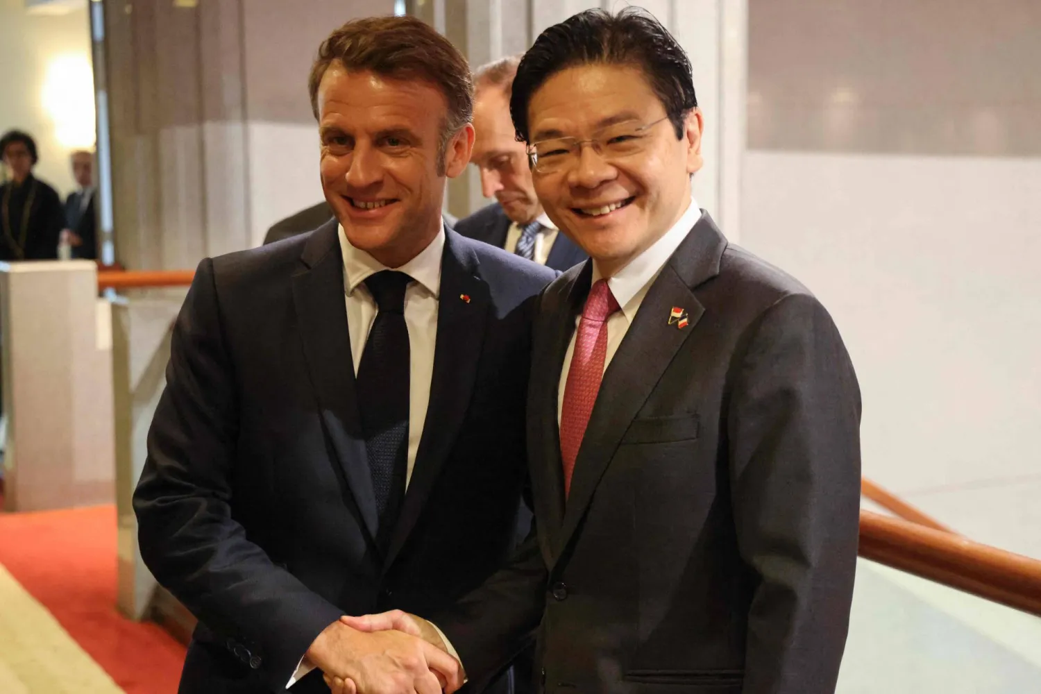 الرئيس ماكرون ورئيس وزراء سنغافورة لورانس وونغ يتصافحان الجمعة في المحطة الأخيرة من جولة الأول في منطقة جنوب شرقي آسيا (أ.ف.ب)
