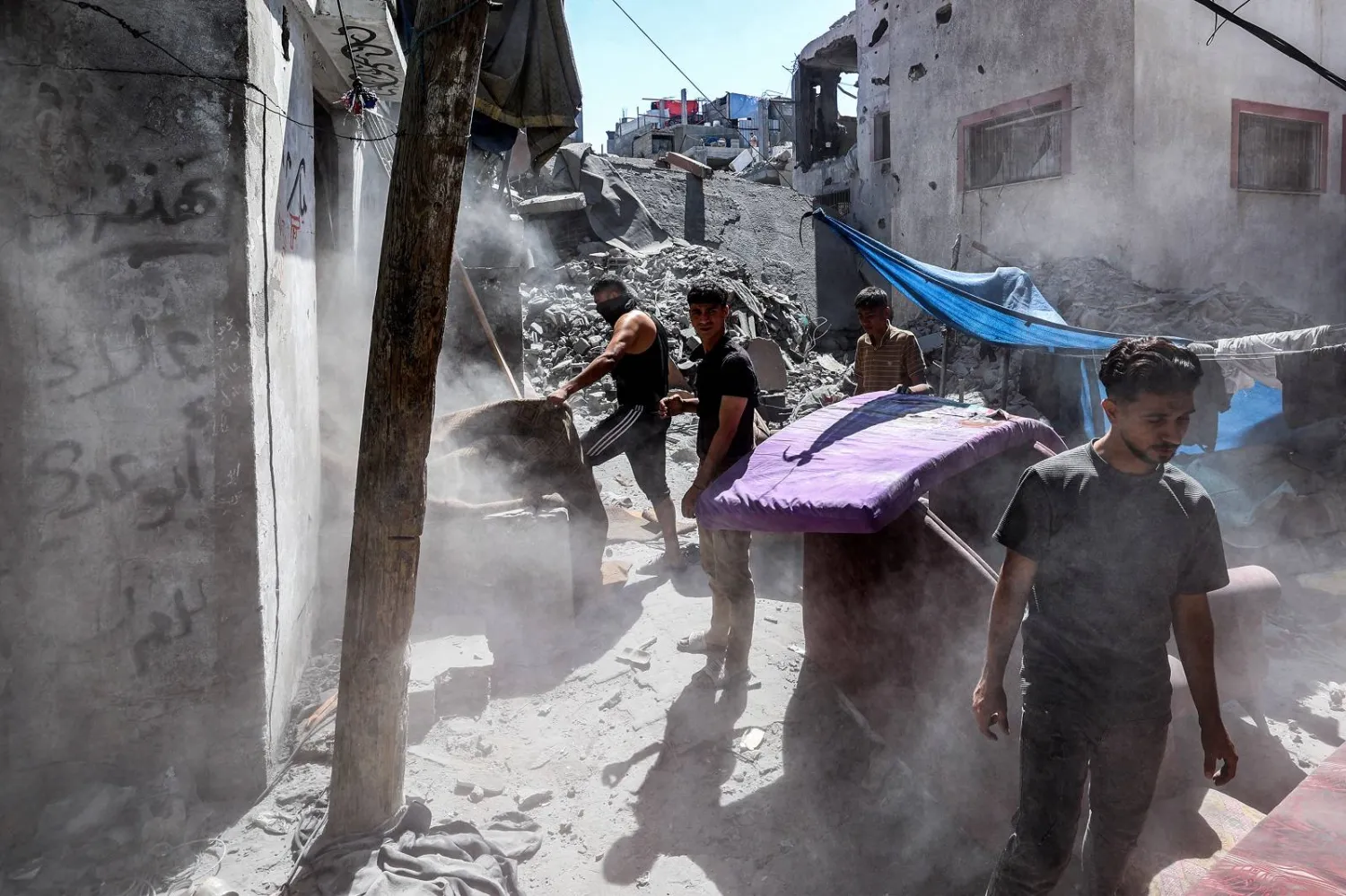 أشخاصٌ يتفقدون أنقاض مبنى مُدمر إثر قصف إسرائيلي على مخيم البريج للاجئين في وقت سابق  (أ.ف.ب)