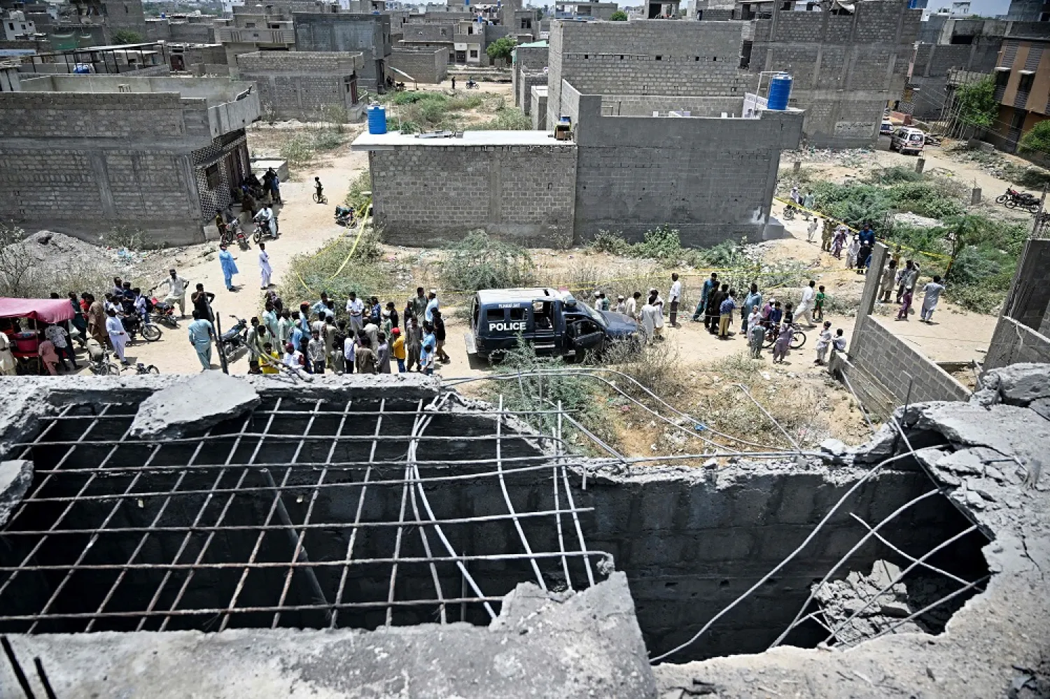 Residents gather as police personnel inspect the site where an alleged drone was shot down in Karachi on May 8, 2025. (AFP)