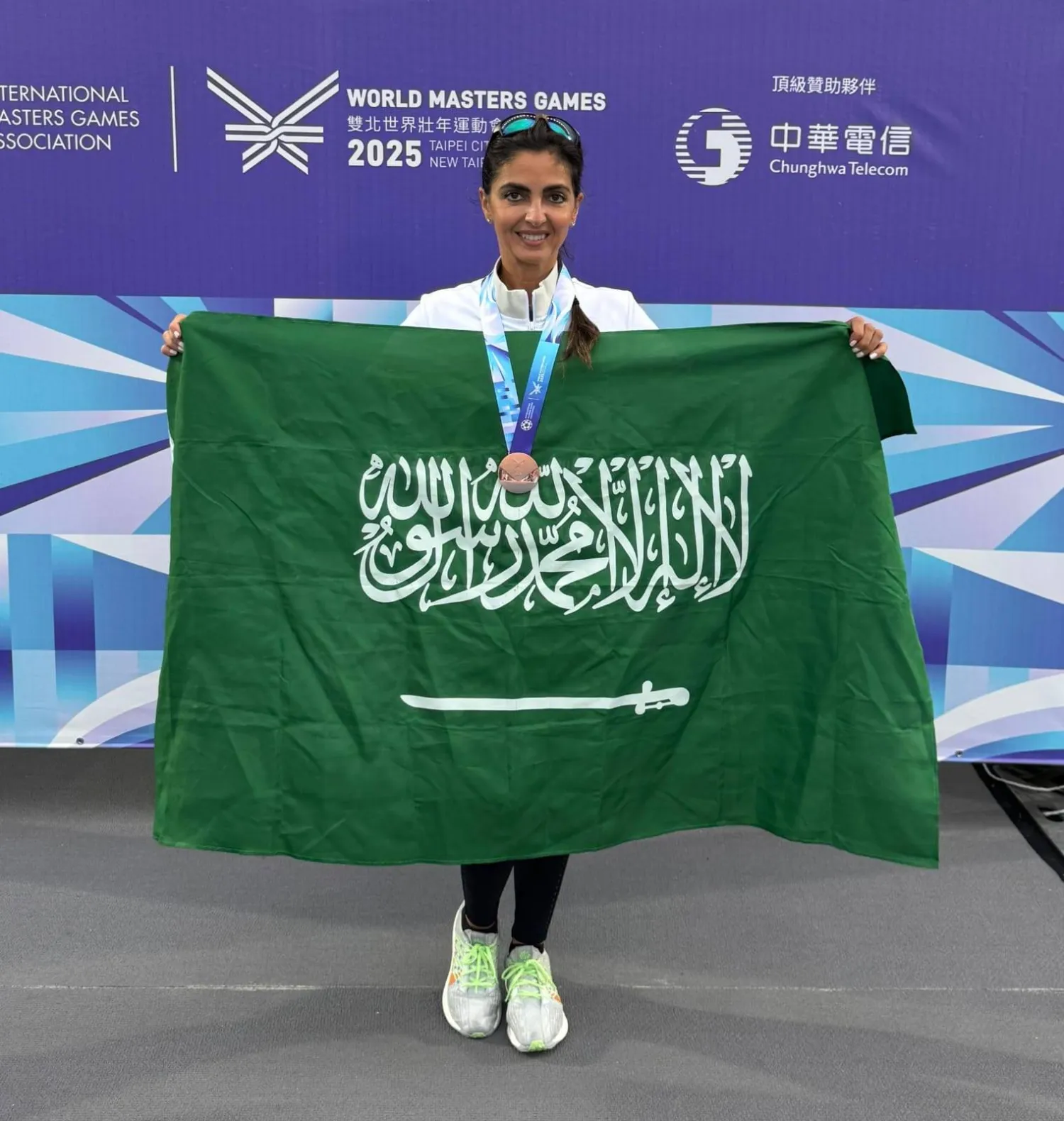 ثريا بن لادن محتفلة بالعلم السعودي عقب تتويجها بالميدالية (الشرق الأوسط)